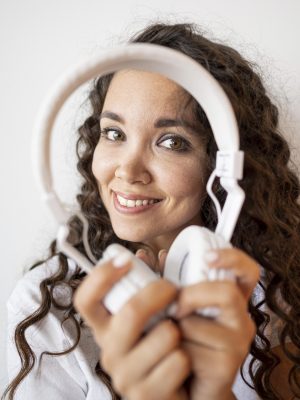 smiley-mulher-encaracolada-segurando-um-par-de-fones-de-ouvido